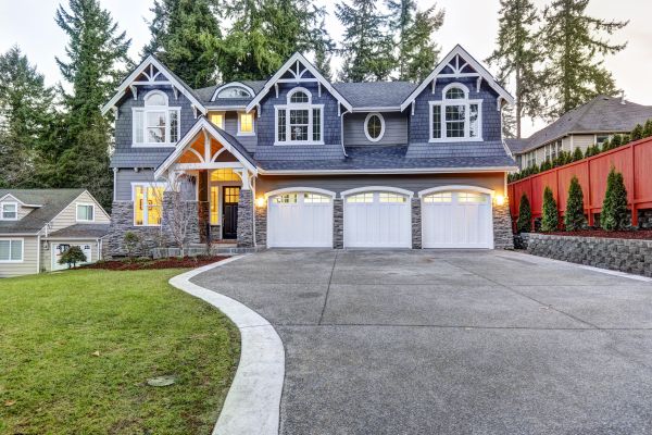 A luxurious home exterior with blue vinyl siding and white trim and three attached garage spaces. This is an example of a good home for co-ownership